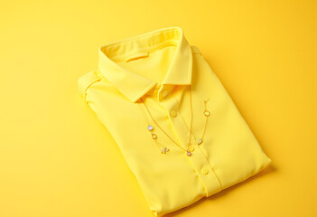 Folded Yellow Shirt with Jewelry on Yellow Background