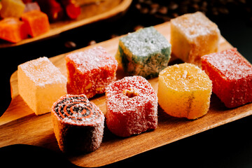Colorful Turkish delights on a wooden tray at a dessert showcase in a vibrant marketplace