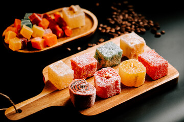 Turkish delights served on a wooden platter with coffee beans and colorful treats in background