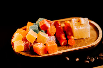 Delightful assortment of Turkish lokum candies on wooden platter against dark backdrop