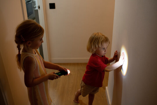 Children playing with a flashlight on the wall at home indoors