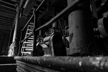 Industrial machinery in an abandoned warehouse showcases rustic charm and decay in black and white
