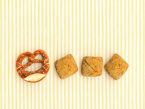 Pretzel and bread rolls in a row on striped background symbolizing contrast