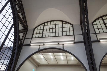 a renovated industrial-style hall, showing the architectural detail of large arched windows, a...