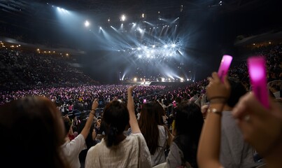 K-pop concert, crowd of fans cheering, glowing light sticks, dynamic stage lighting