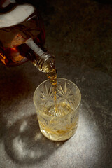 Whisky pour from a bottle into a crystal glass.