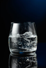 Vodka with ice on a black reflective background.