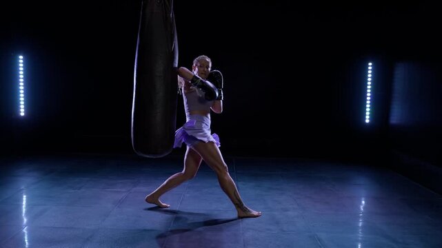 Kickboxing, woman fighter beats a punching bag, training day in the boxing gym, pro fighter trains his kicks and punches, strength fit body, super slow motion.