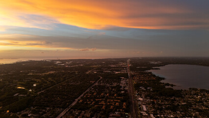 Aerial drone view of Tampa, Florida at sunset with a long road stretching across the city grid under dramatic orange skies, symbolizing the blend of urban structure and natural beauty.