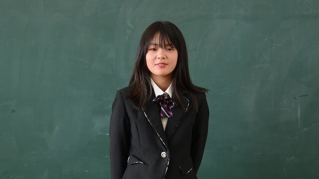 クイズに答える女子学生　学校の教室で○✕を出す教育イメージ