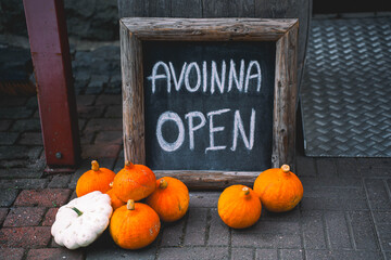 A nordic "Open" -sign decorated by pumpkins and getting ready for festive halloween time.