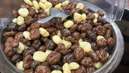 The appearance of milk chocolate and white chocolate-covered dried grapes in a full container.