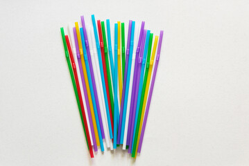 Many colored plastic drinking straws on a light background with a copy space
