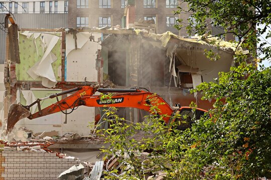 An excavator is carrying out demolition work, dismantling an old building