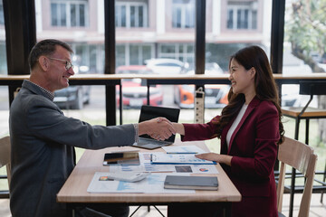 Two businesspeople shaking hands after reaching an agreement during a meeting in a modern office, celebrating their collaboration and partnership