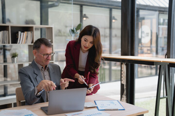 Business people discussing over financial reports showing data charts using laptop and smartphone in the office, teamwork and cooperation concept