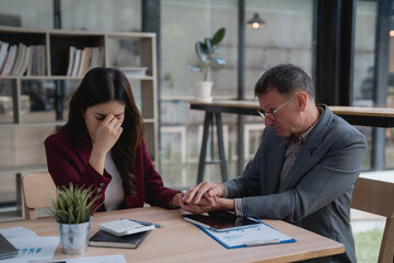 Businessman holding the hands of a stressed businesswoman, providing support and comfort after her business mistake in the office, illustrating the challenges of workplace failure