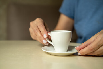  Close up of female hands holding little white cup of tea or coffee.