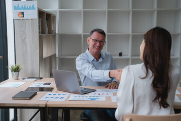 Senior manager shaking hands with a new employee after a successful job interview, showing mutual respect and starting a positive working relationship in a modern office environment