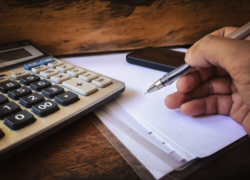 Hand writing on paper with calculator and smartphone for financial calculation