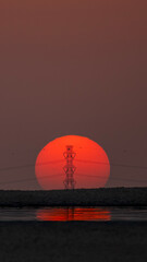 Doha, Qatar - September 7, 2025: Power transmission line poles against the sun. Sunset view with high tension pole 