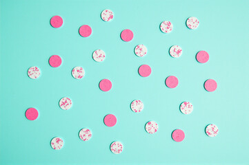 Bunch of pink and white confetti on a turquoise background.