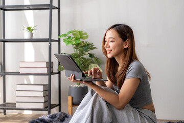 A woman is sitting on the floor with a laptop in front of her
