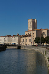 Fototapeta premium Saint-Sauveur Church and surrounding historic buildings along the canal in La Rochelle, France, near the Old Port (Vieux Port), on a clear sunny day