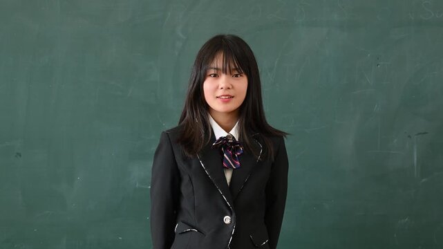 クイズに答える女子学生　学校の教室で○✕を出す教育イメージ