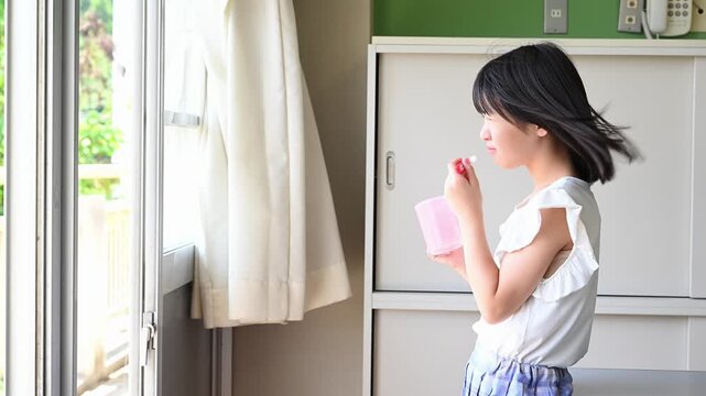 学校の教室で給食後に歯磨きをする小学生の女の子