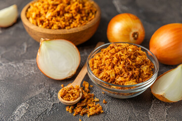 Crispy fried onions in a bowl on a wooden table. Roasted Onions. Seasoning for dishes. Spices. Salad dressing. Space for text. Copy space