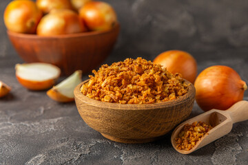 Crispy fried onions in a bowl on a wooden table. Roasted Onions. Seasoning for dishes. Spices. Salad dressing. Space for text. Copy space