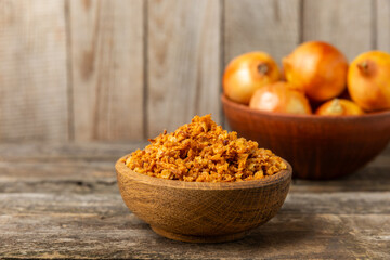 Crispy fried onions in a bowl on a wooden table. Roasted Onions. Seasoning for dishes. Spices. Salad dressing. Space for text. Copy space