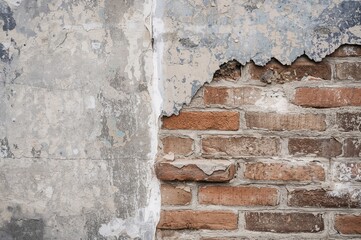 Fototapeta premium A weathered brick wall corner displays flaking plaster and eroded bricks, highlighting surface deterioration