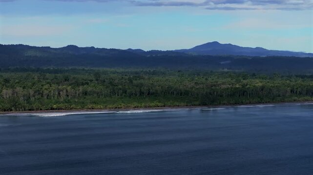Untouched remote pristine coastline waves Harbor View Papua New Guinea PNG aerial drone Cape Wom Dogreto Bay Madang Wewak Kavieng Vanimo Tufi sunny blue sky tropical beach shoreline circle right