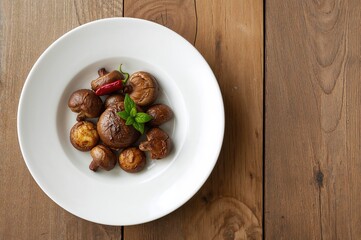 A portion of roasted mushrooms seasoned with garlic and chili, presented on a white dish atop a rustic table, featuring space for text. Nutritious and in-season meal.
