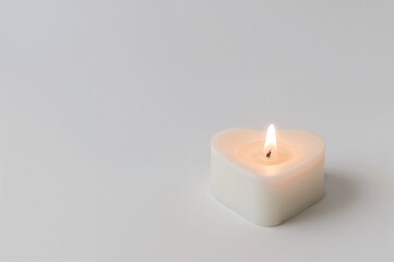 A single glowing heart-shaped candle against a plain background.