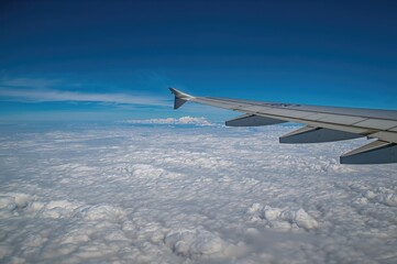 Fototapeta premium View from an aircraft wing over a sea of clouds under a clear blue sky