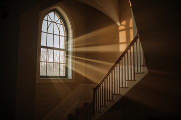 Obraz premium Warm afternoon light streams through stained glass, illuminating the stairs leading up to the choir loft in a coastal chapel.