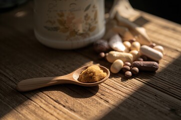 A wooden spoon filled with dietary supplements rests on a wooden surface. Dietary supplements support a balanced and healthy lifestyle.