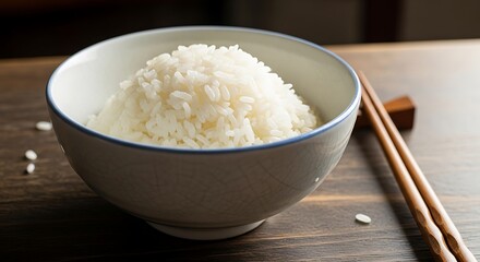 Bowl of perfectly cooked white rice presented with chopsticks on wood