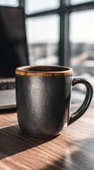 Ceramic mug on a wooden desk next to a laptop, bathed in sunlight from a window
