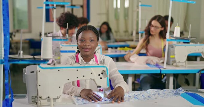 African young adult gen z lady female wear tape around neck look cam indoor class room learn good craft skill sewing machine happy teen girl pupil staring camera do casual pose new college day place