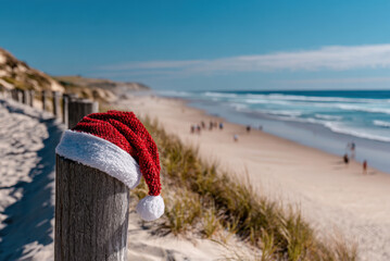 a Christmas hat on the beach in Australia, with white sandy beaches and clear blue skies as the background