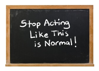 Fototapeta premium Stop acting like this is normal written in white chalk on a black chalkboard with a wooden frame