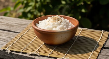 Steaming bowl of rice with sesame seeds rests on bamboo placemat