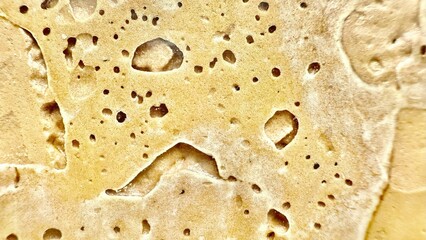 porous beige stone macro texture with natural holes and shadows creating abstract organic surface ideal for wallpaper or editorial background