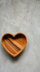 Wood heart bowl on mottled gray surface, warm tone, eye-level, simple composition, lots of space above the bowl