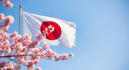 The Japanese flag waving gracefully in the wind with a branch of cherry blossoms in the spring