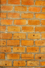 Rough texture of a weathered red brick wall with an old, solid pattern of brown and orange cement